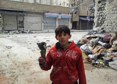 Сирийский мальчик показывает осколок мины.