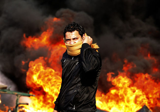 Египет. Демонстрант стоит перед горящей баррикадой 