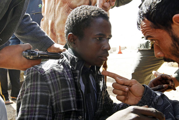 Мятежники привели молодого человека под дулом пистолета, которого они обвинили в том, что он сражался на стороне ливийского лидера Муаммара Каддафи