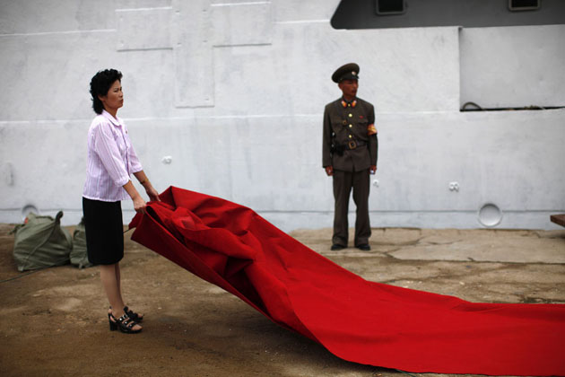 Женщина готовит красный ковер для подготовки выхода с круизных судов в Северной Корее.
