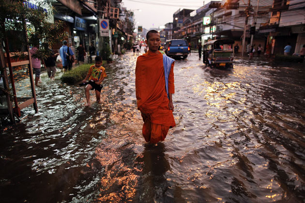 Буддистский монах идет по затопленной улице в центре Бангкока, Таиланд.