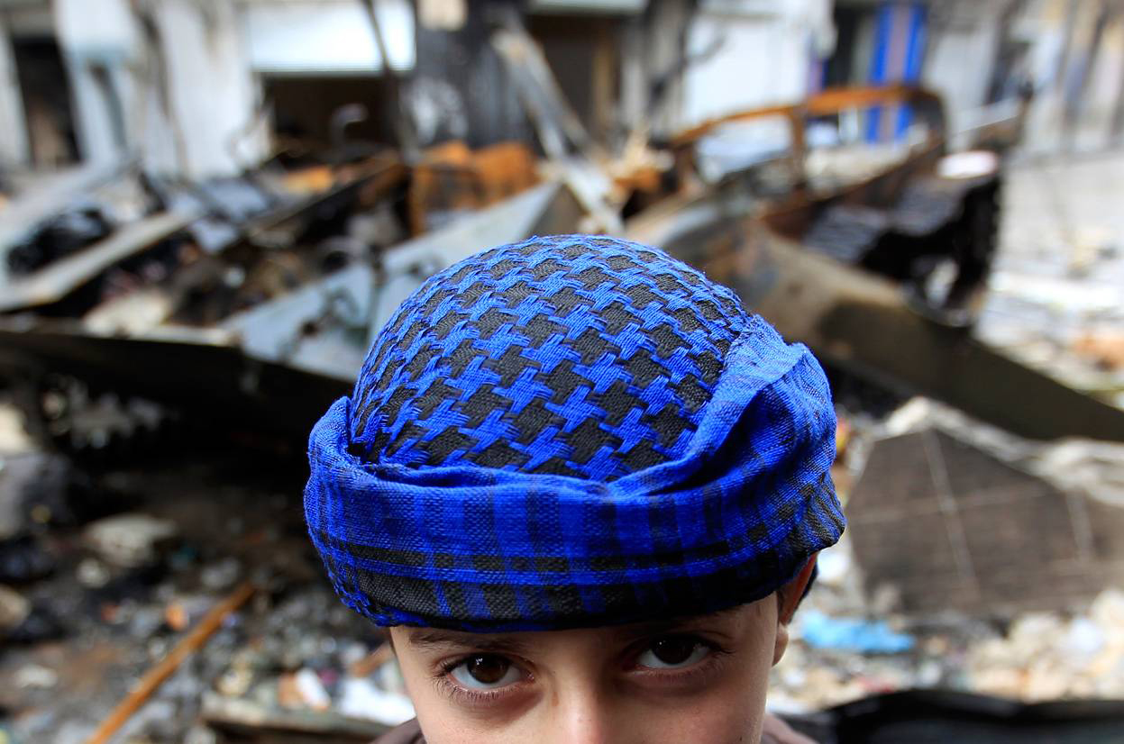 Сирийский мальчик перед поврежденным бронированным автомобилем. г. Хомс Reuters / Ahmed Jadallah