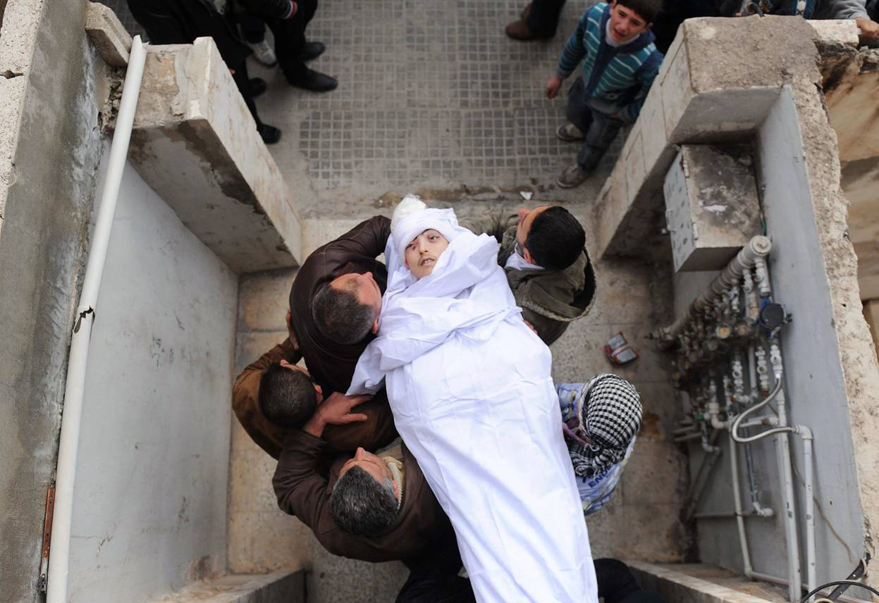 Сирийцы выносят тело человека. г. Идлиб 23 февраля 2012 года. Bulent Kilic / AFP / Getty