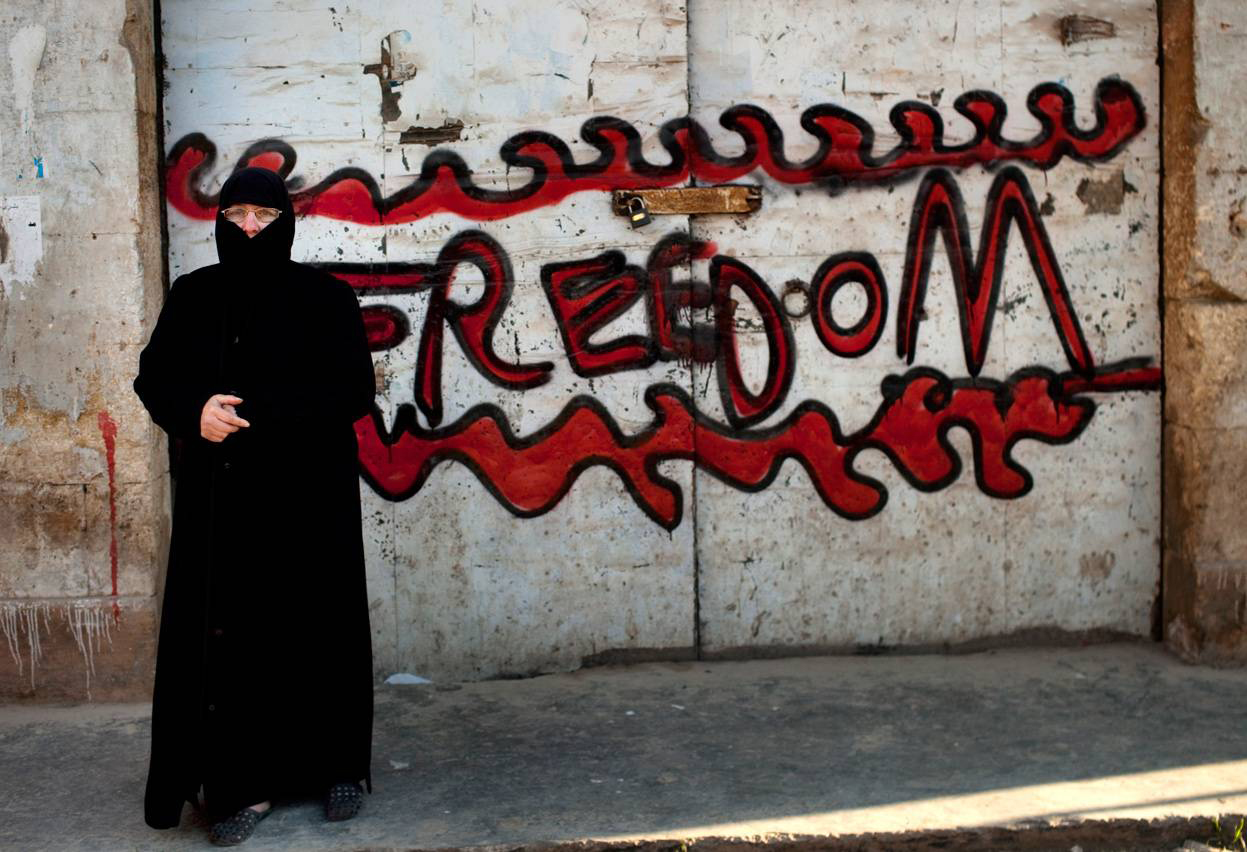 Женщина стоит рядом с граффити, где написано «Свобода», во время проведения демонстрации против законной власти Сирии. AFP Photo / Rodrigo Abd